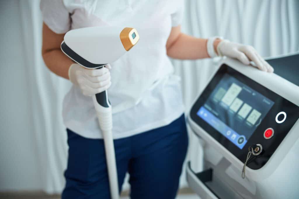 Cosmetologist in nitrile gloves holding a beauty device handle